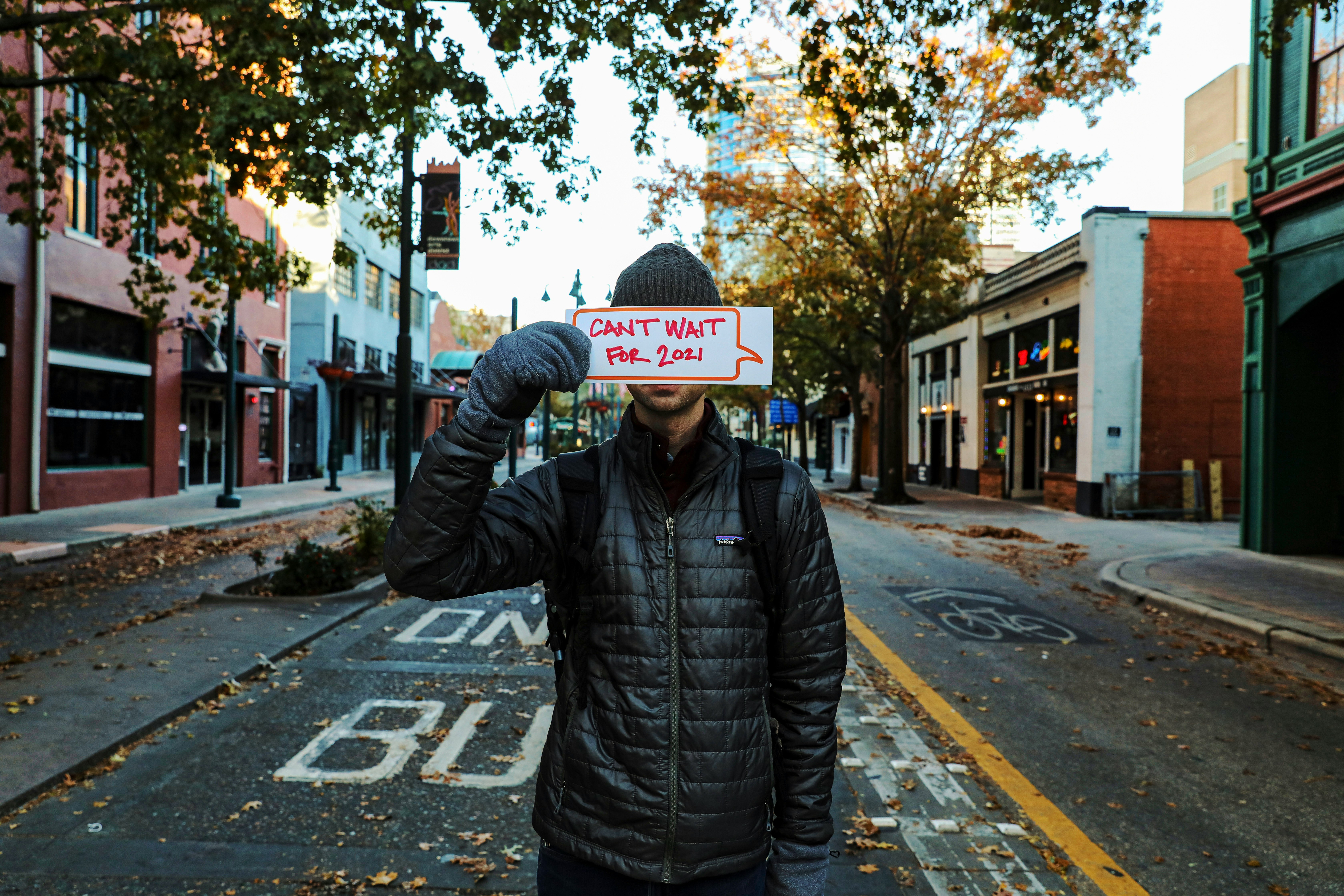 man in black leather jacket standing on pedestrian lane during daytime